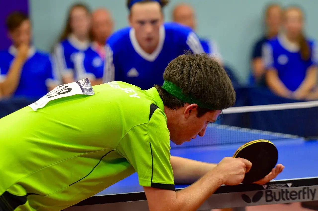 Bordtennisspiller i grøn trøje klar til at serve